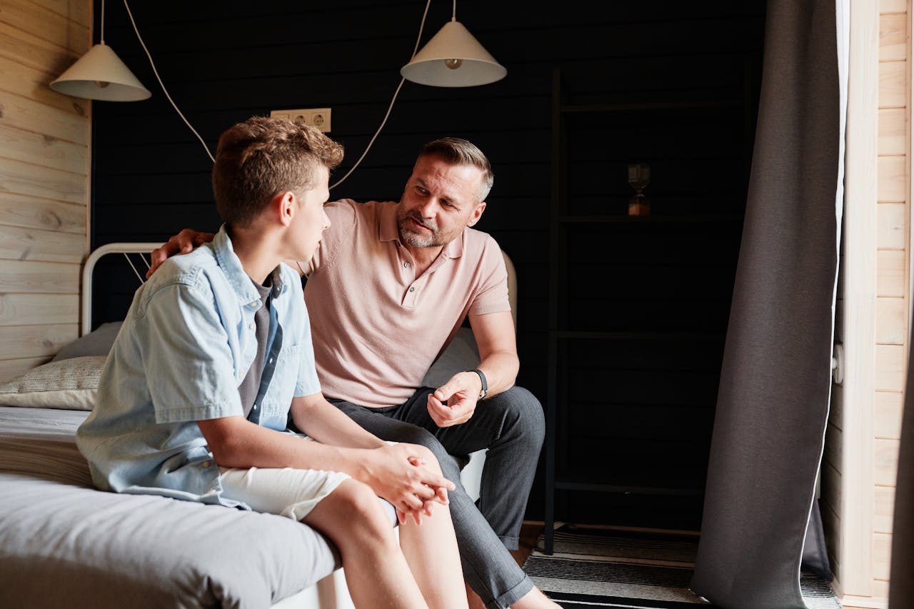 Mastering the First Impression: Your intriguing post title goes here A father bonding with his teenage son in a cozy bedroom, sharing advice and conversation.
